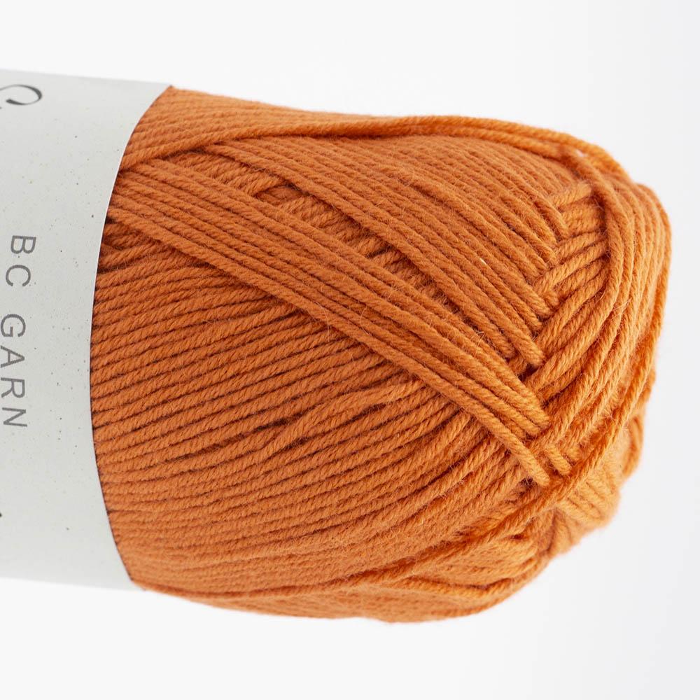Garnknäuel aus Wolle in kräftigem Orange, gedrehte Strickoptik auf der Spule
