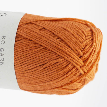 Garnknäuel aus Wolle in kräftigem Orange, gedrehte Strickoptik auf der Spule