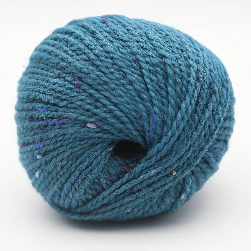 Garnknäuel in Blau mit kleinen Farbklecksen, gleichmäßige Wicklung und zentrales Loch