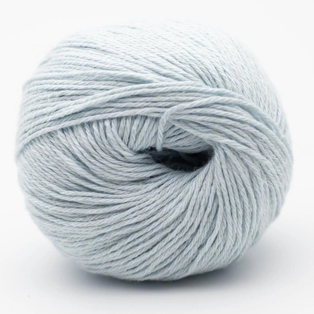 Garnknäuel in Hellgraublau mit sichtbarem Wickelkern, gleichmäßige Strickfäden