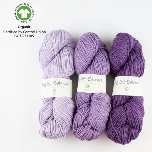 Mehrere Wollknäuel in Violett mit Etiketten „Bio Balance“ und GOTS-Aufdruck